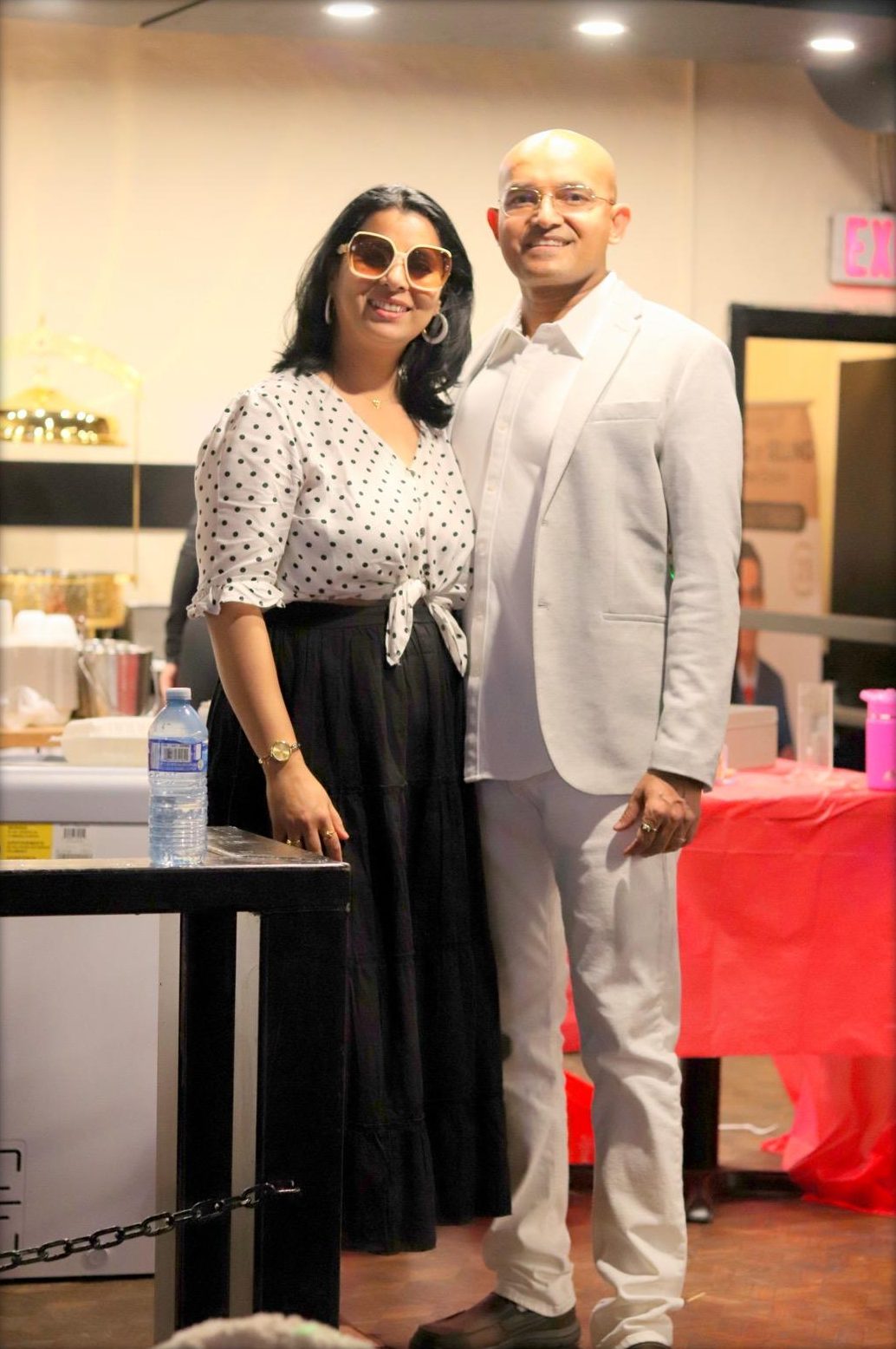 The evening's hosts, a man in a white suit and a woman in a polka-dot blouse and oversized sunglasses