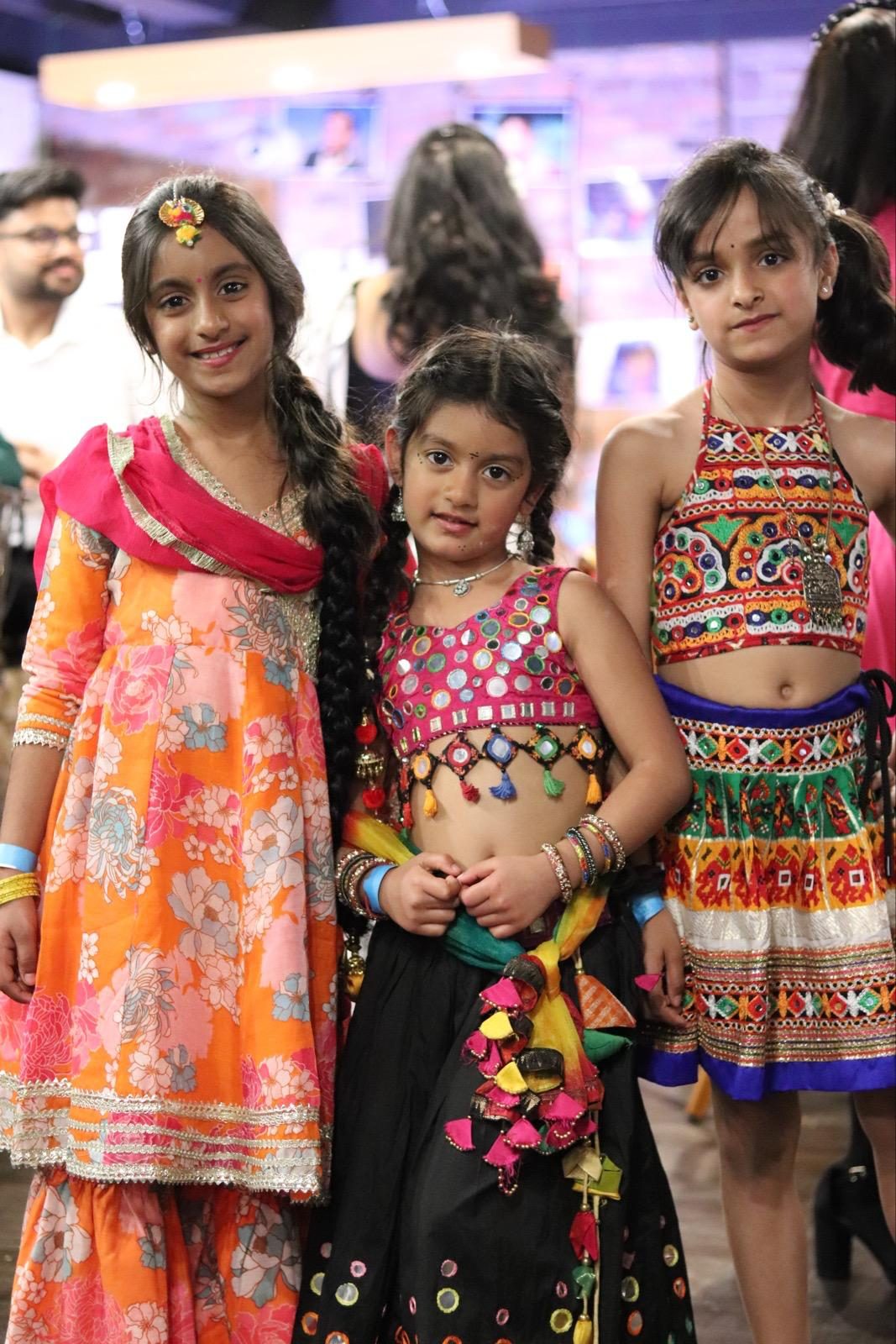 Three young girls in bright festive outfits posing together