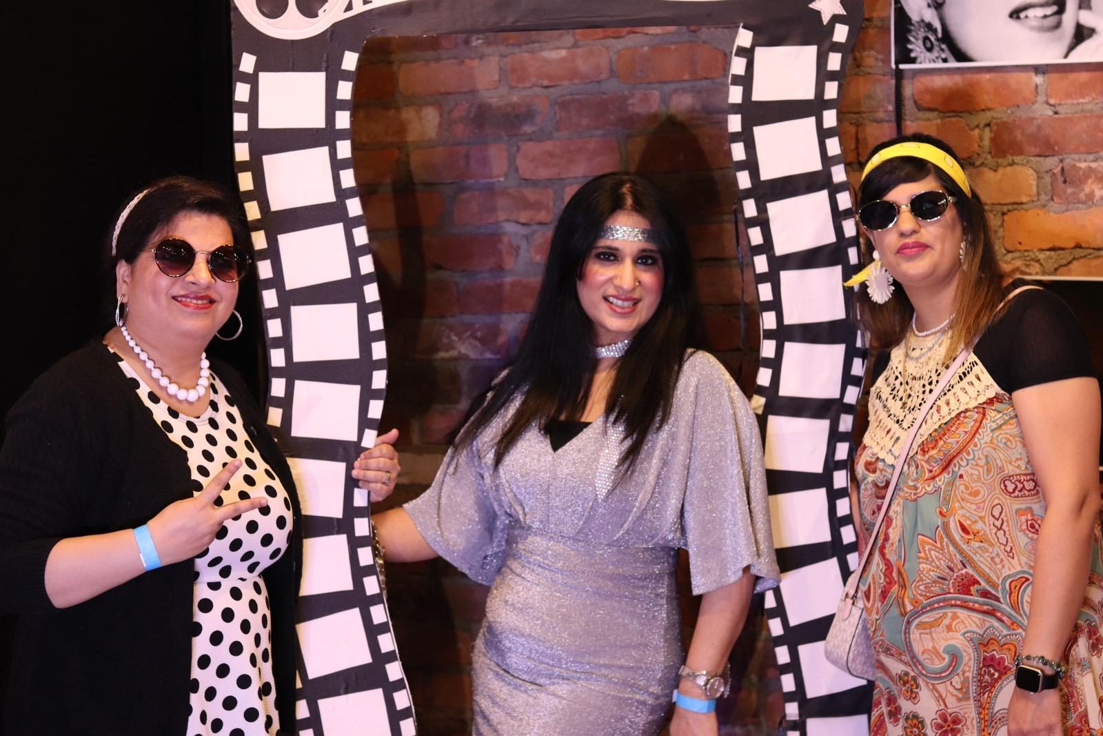 Three friends in retro outfits posing inside a black and white film-strip photo frame