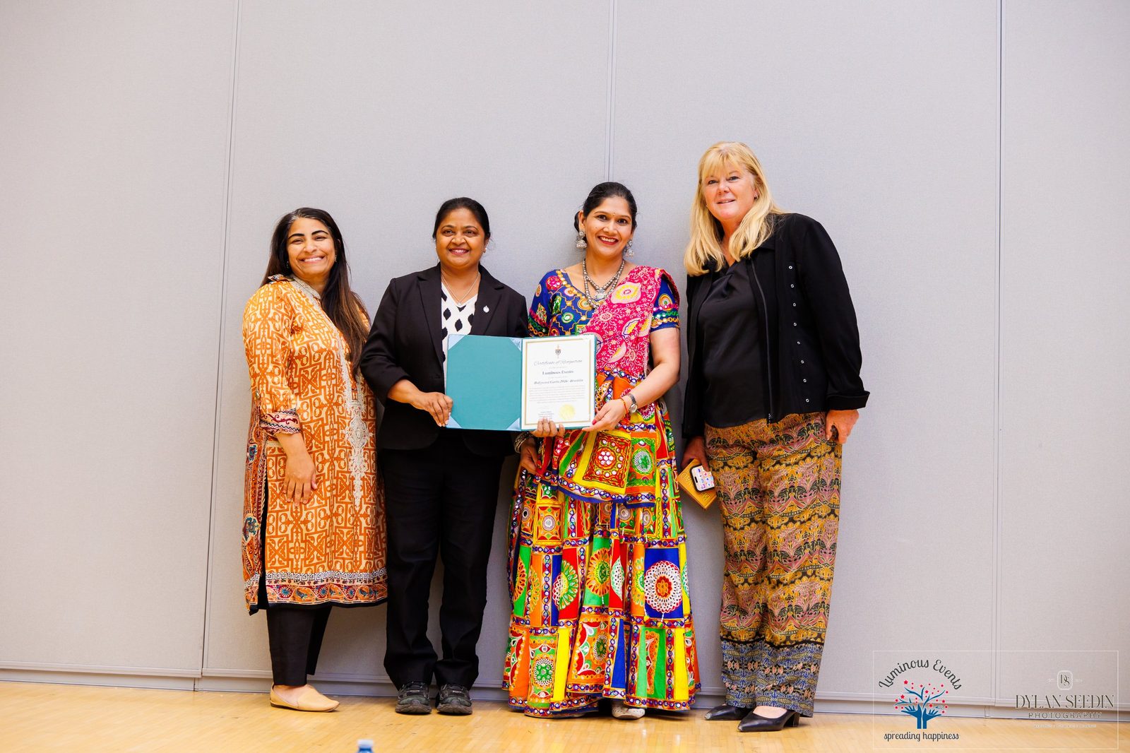 Four people on stage holding a Certificate of Recognition presented to Luminous Events for Bollywood Garba 2026 – Brooklin by Juanita Nathan, Member of Parliament for Pickering-Brooklin