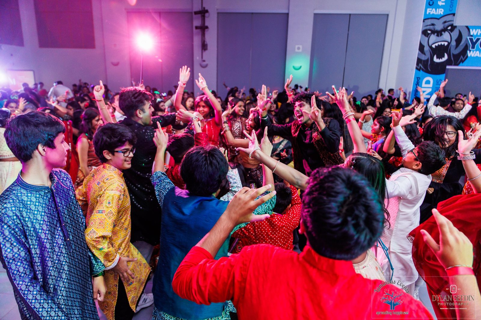 Guests dancing with hands in the air under purple stage lights