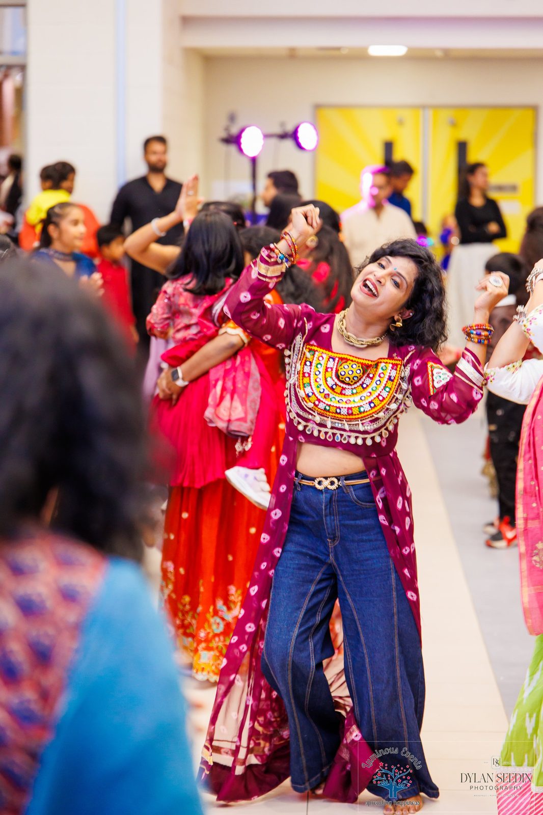Guest dancing joyfully in the hallway in a maroon bandhani jacket