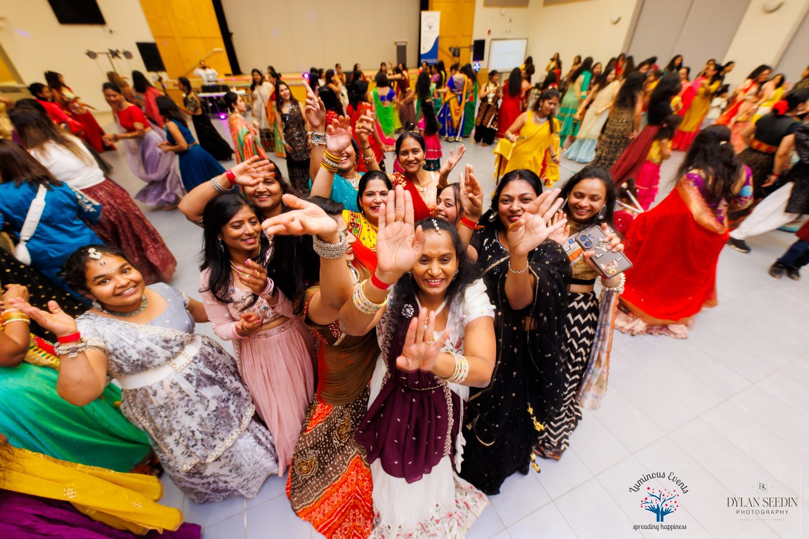 Smiling dancers reaching toward the camera on the Garba dance floor