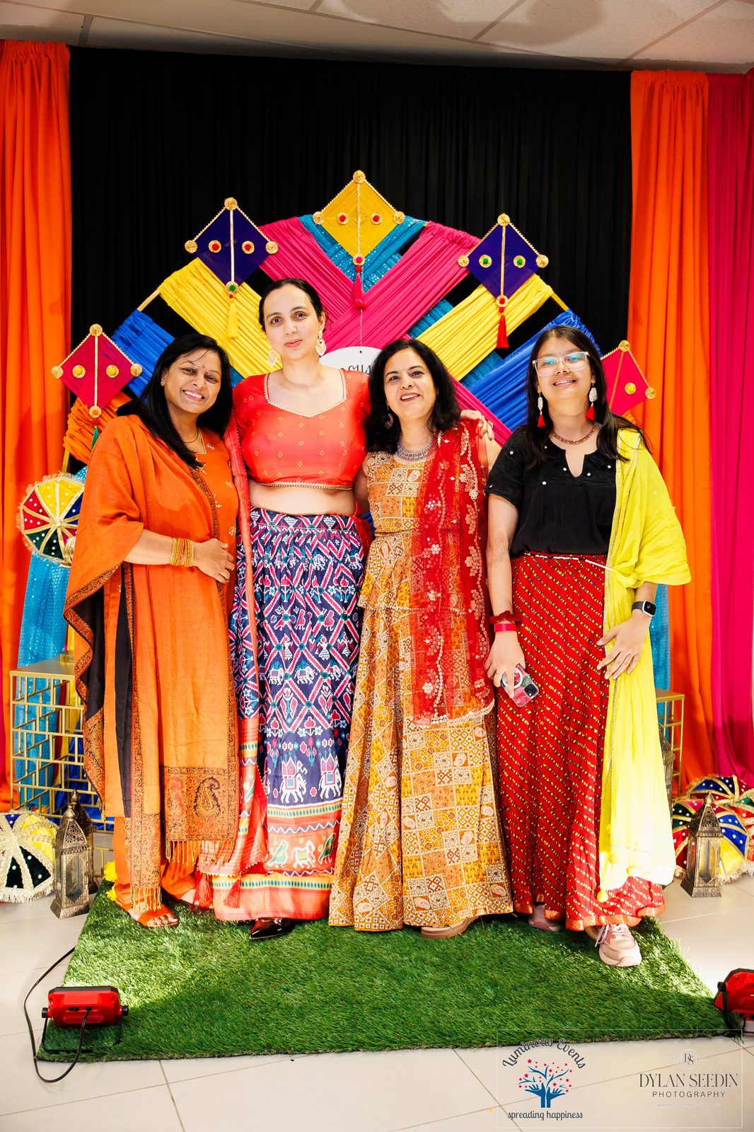 Four guests posing in front of the colourful kite photo backdrop