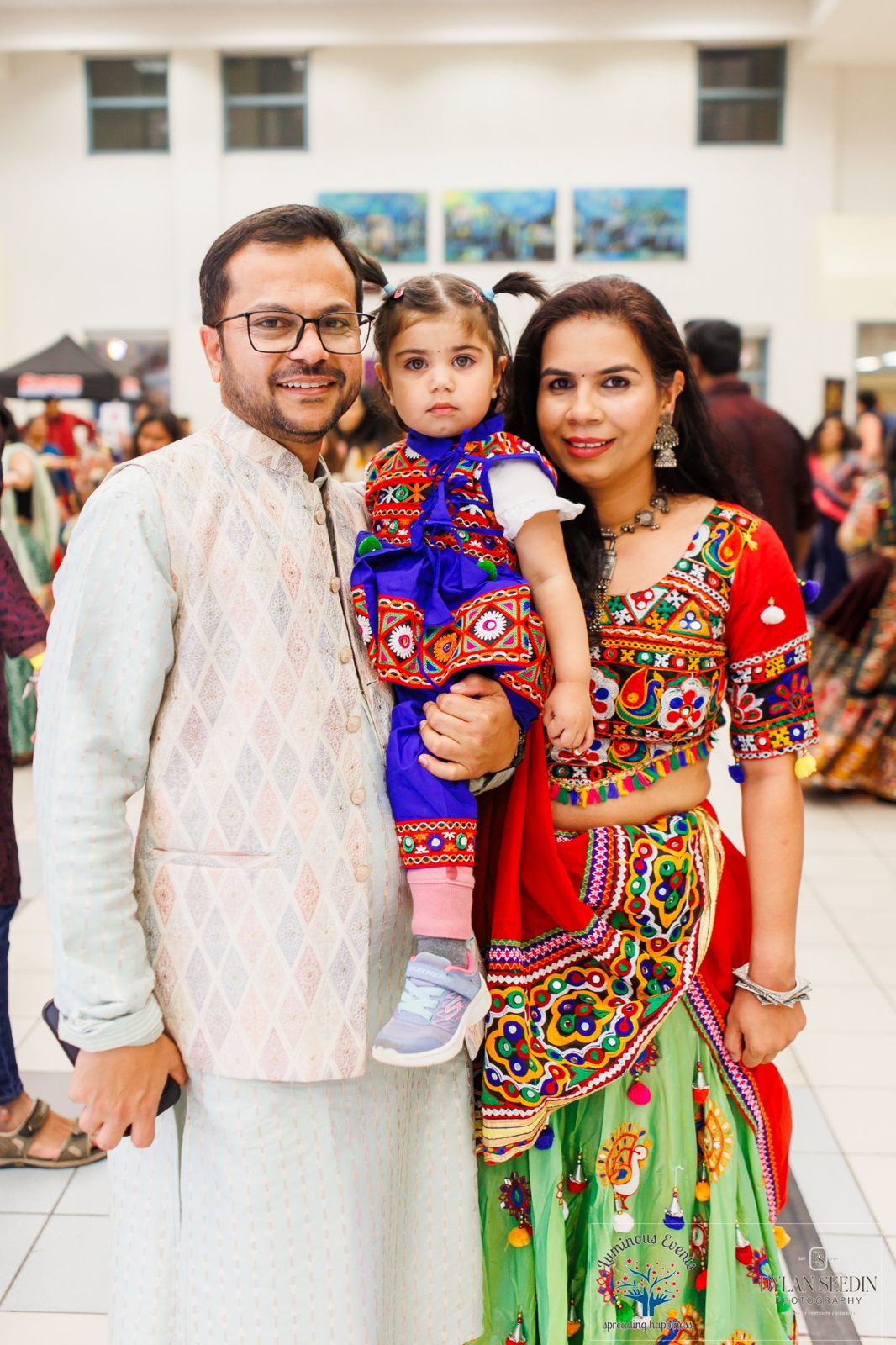A father and mother with their toddler, all dressed in festive traditional outfits, at Bollywood Garba Pickering