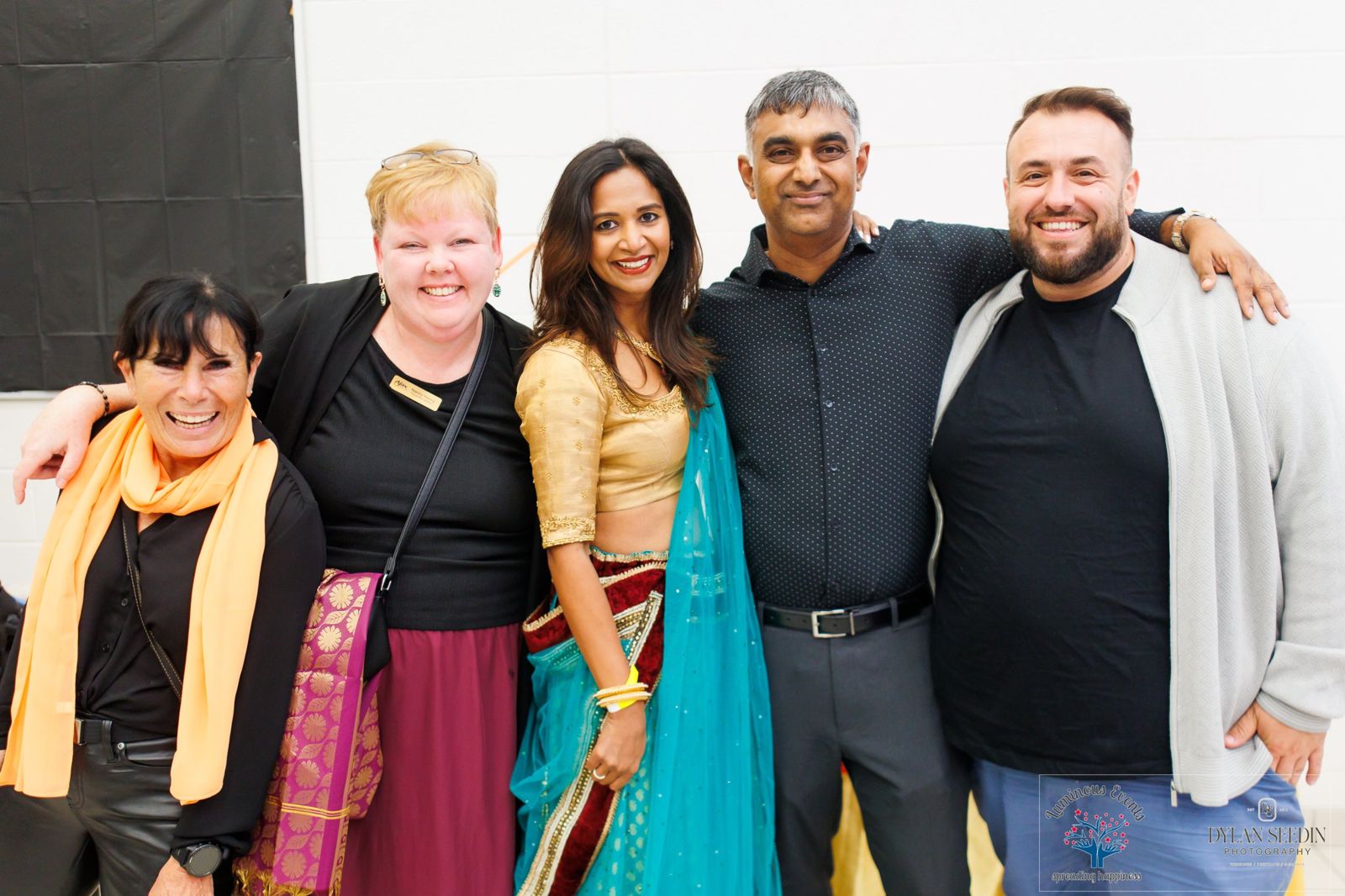 Event hosts and guests laughing together with arms around each other