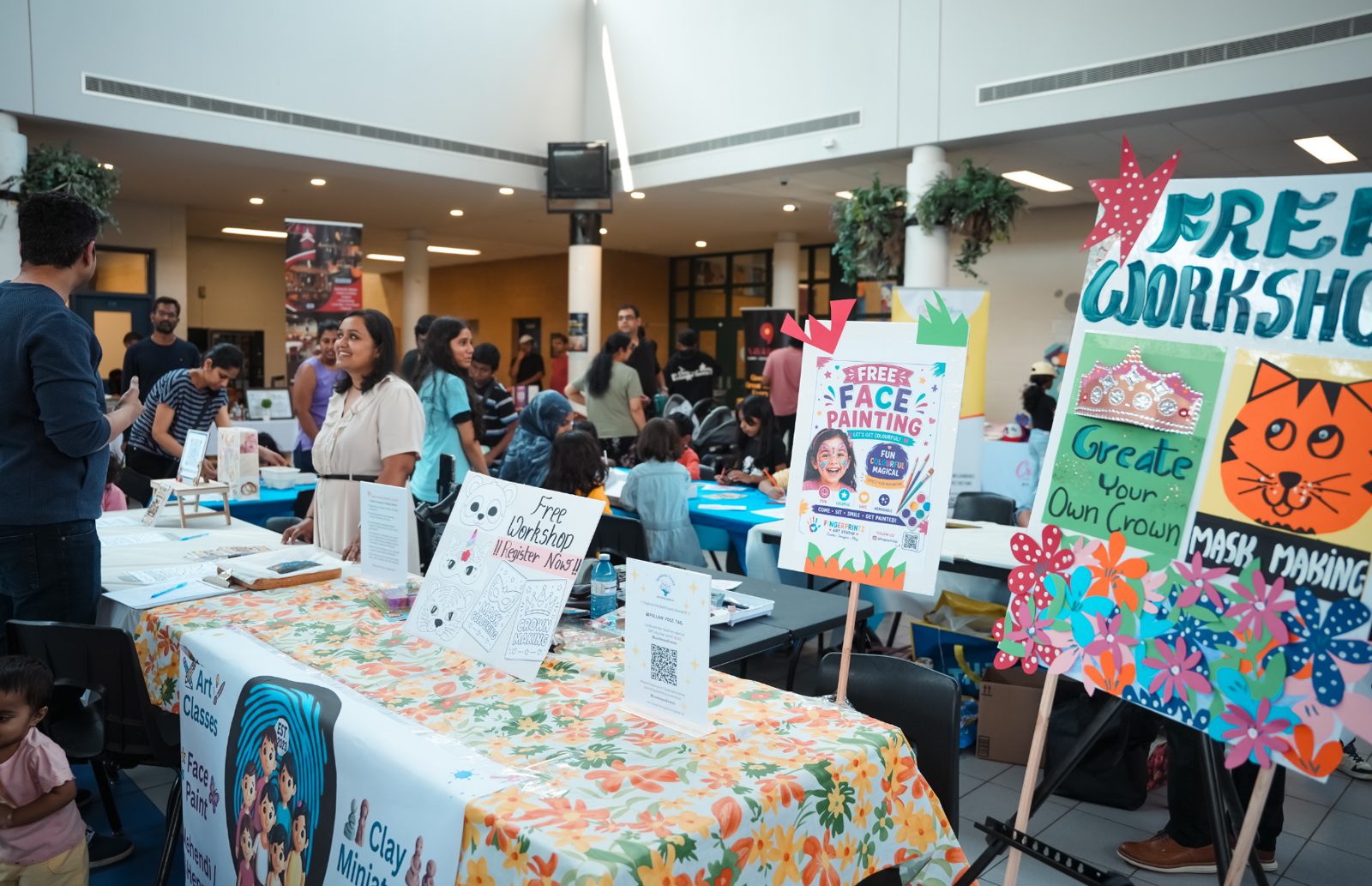 The art classes and free workshop table with face painting and mask-making signs