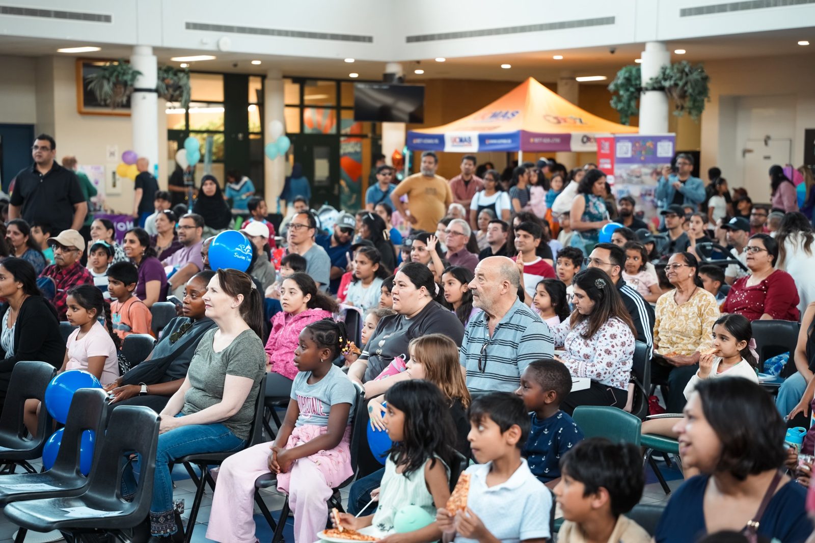 A large, diverse crowd of children and families watching the magic show at the Young Minds Explore and Grow Expo