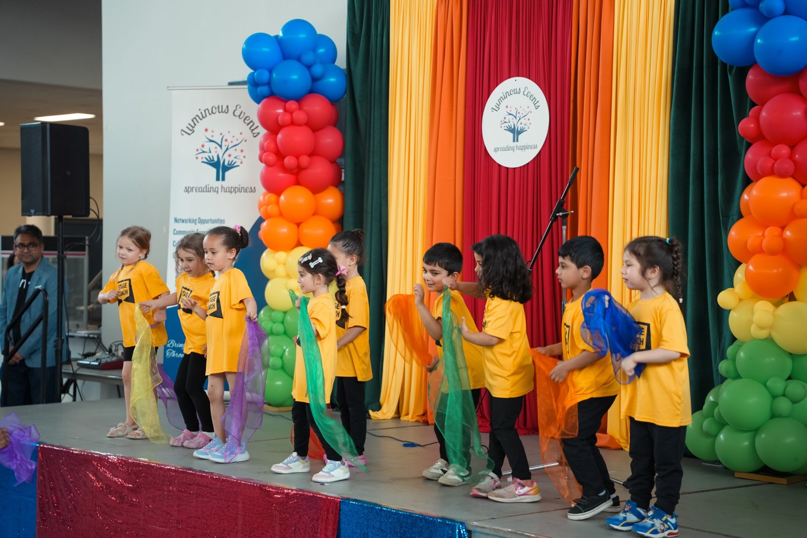 Children dancing with colourful scarves on stage at the Young Minds Expo